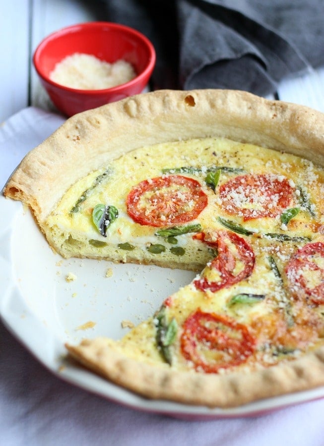 This savory roasted tomato and asparagus quiche has the best flavors of summer. A simple and easy dish you can make for breakfast, lunch or dinner! gardeninthekitchen.com
