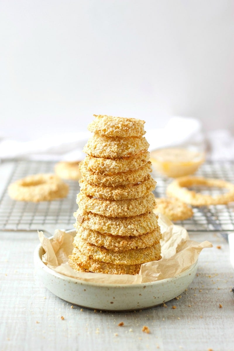 a stack of baked onion rings on a small beige plate.