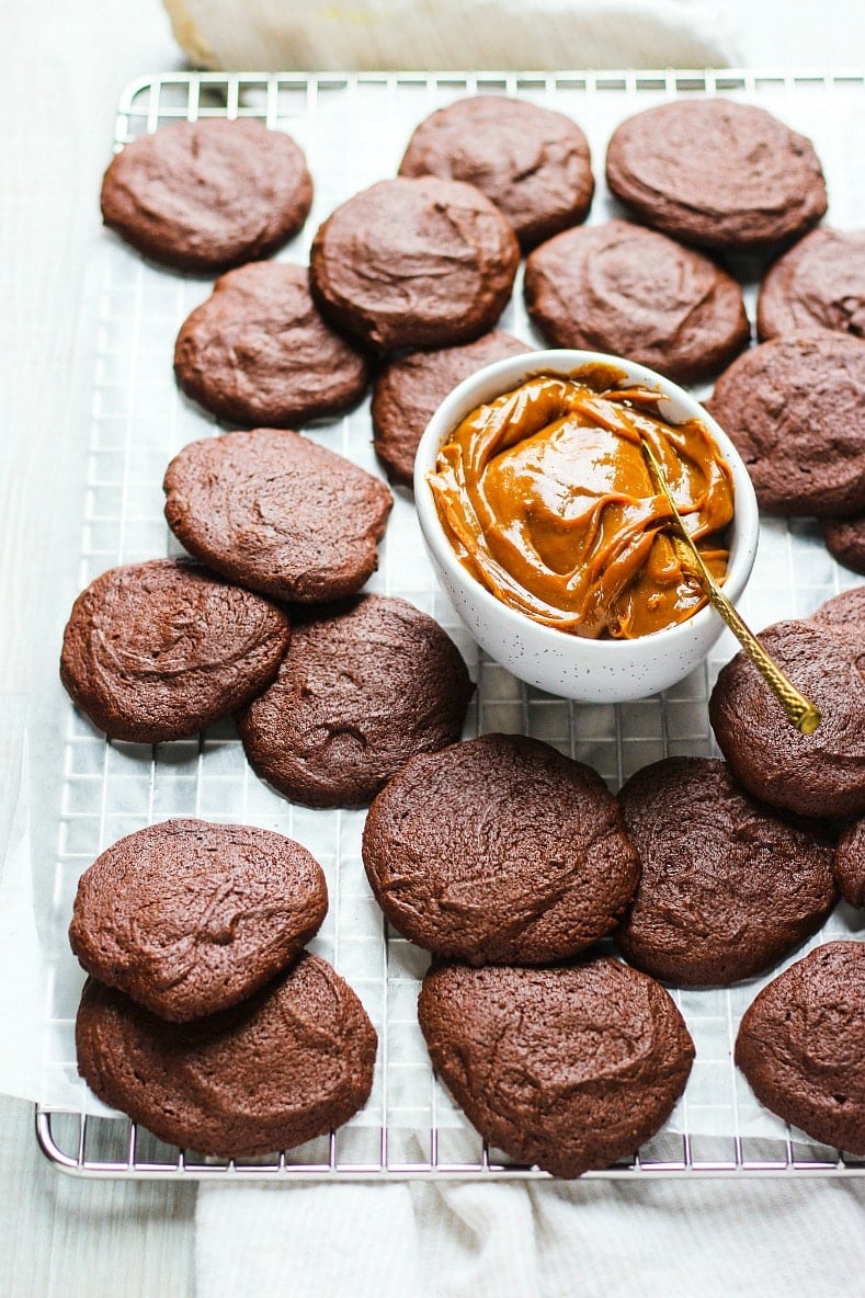 Chocolate sandwich cookies with a small white bowl of dulce de leche cream.