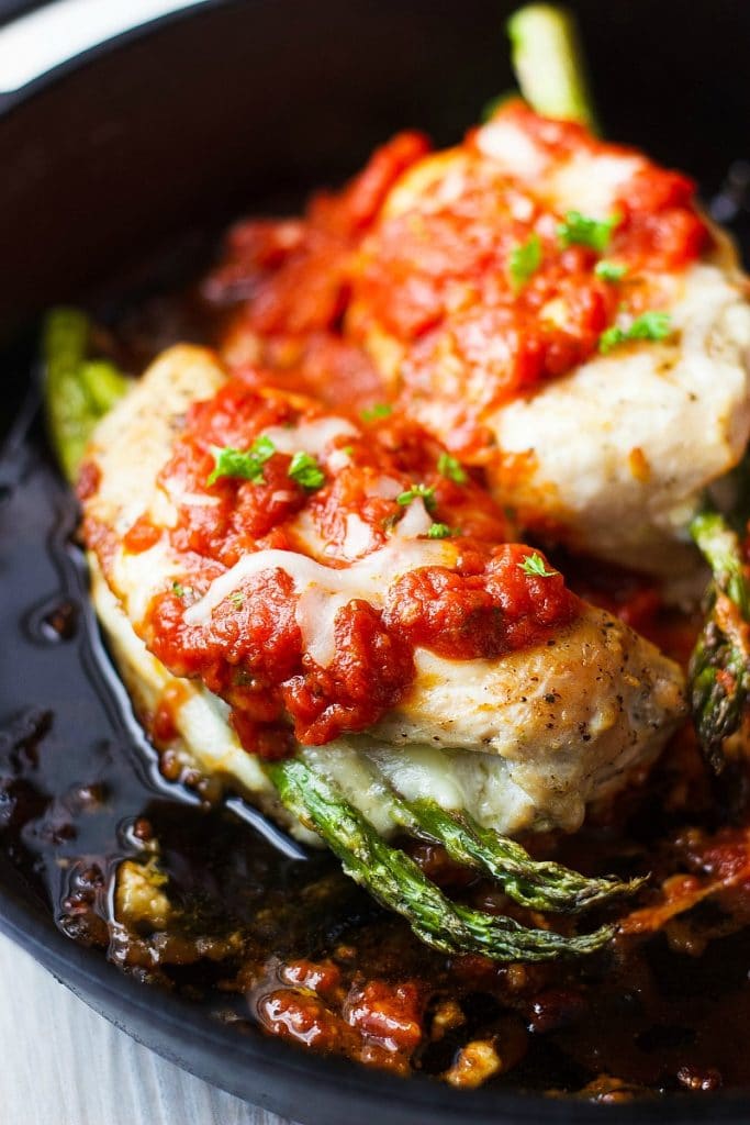Baked Chicken Parmesan stuffed with asparagus and cheese in a cast iron skillet