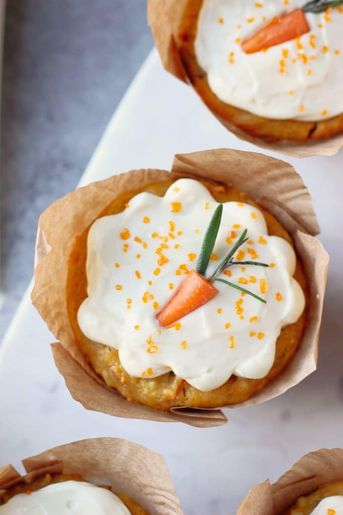Gluten Free Carrot Cake Cupcake with cream cheese frosting. A mini carrot on top. 