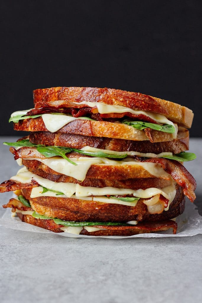 Toasted slices of bread with layers of bacon, cheese and spinach
