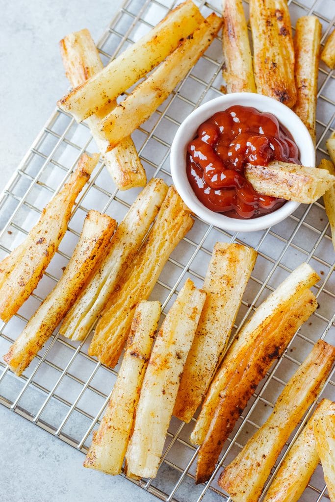A small bowl with ketchup and slices of the yuca root baked and cooled in a cooling rack.