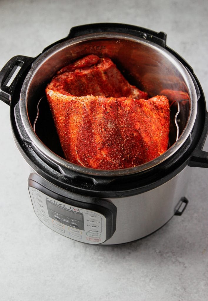 rack of ribs seasoning inside of an instant pot, ready to be cooked.