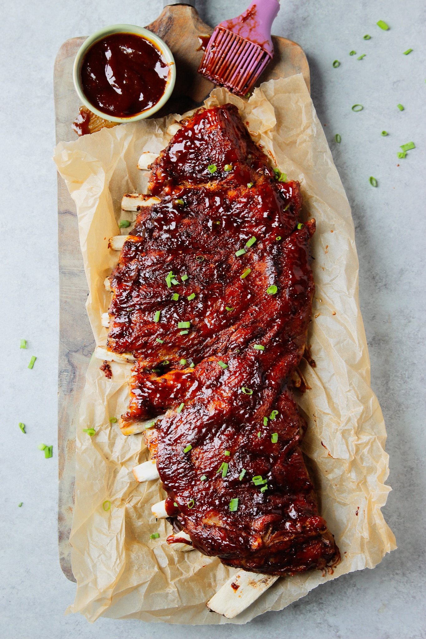 a rack of cooked bbq ribs on a parchment-lined cutting board.