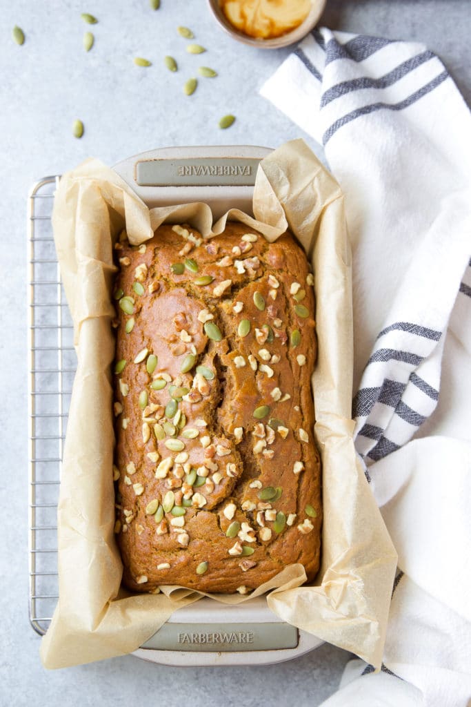 A loaf of healthy bread topped with nuts in a loaf pan