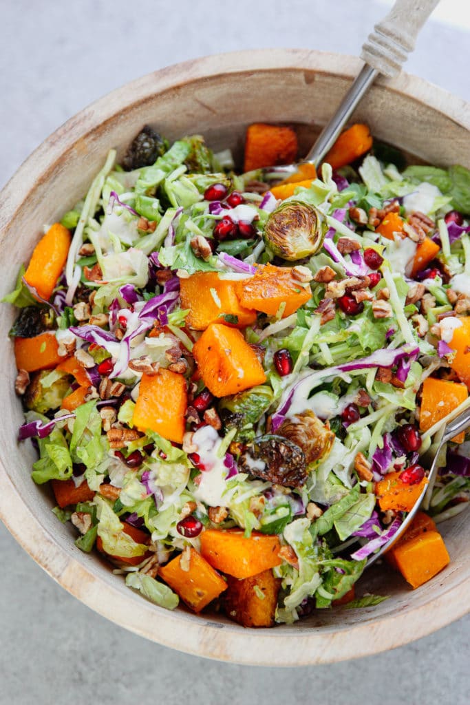 Garlic Roasted Vegetables Salad in a wooden bowl with dressing tossed