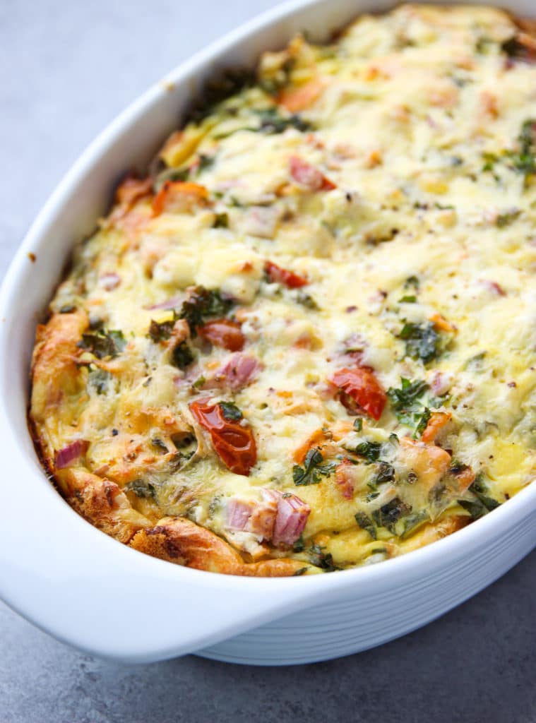 Smoked salmon, eggs, cheese and vegetables in a white deep pan