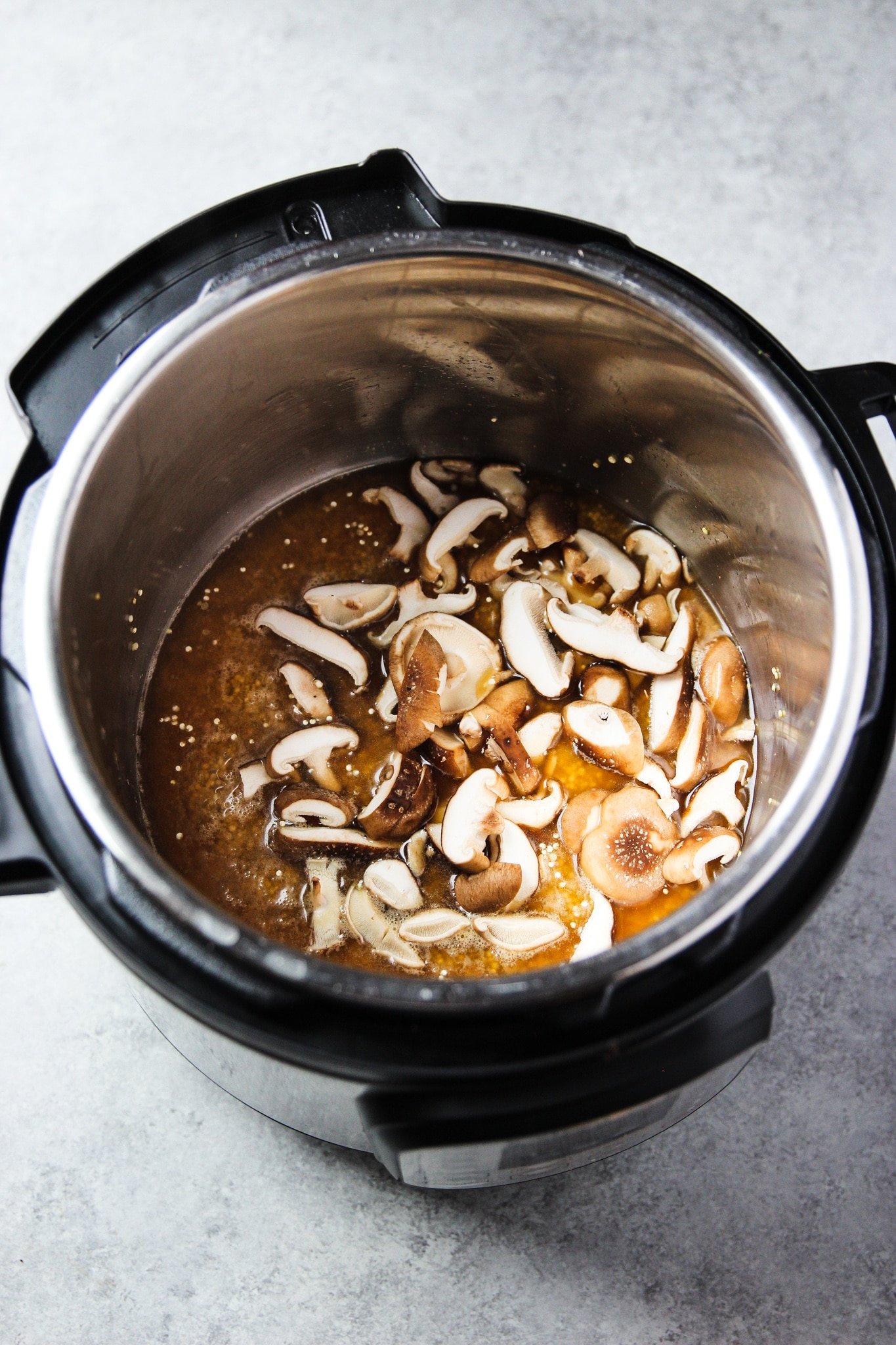 raw mushrooms and broth in the bowl of an instant pot.