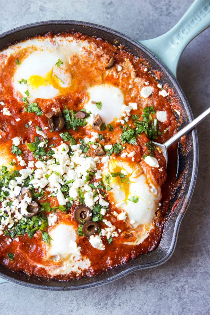 Shakshuka in a skillet with a big spoon