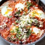Shakshuka or sometimes called shakshouka consists of poached eggs in tomato sauce mixture topped with olives, parsley and feta cheese