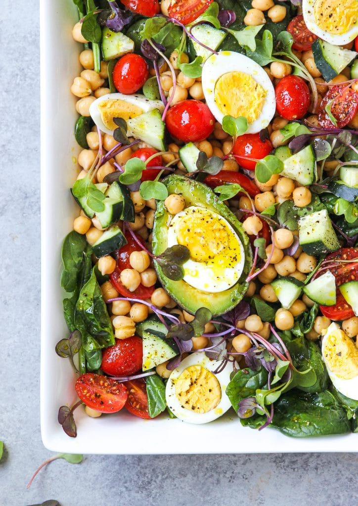 chickpea salad platter with fresh grape tomatoes, cucumber slices, avocado and hard boiled eggs