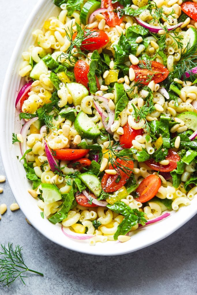 pasta salad with fresh spinach, tomatoes and cucumbers, served on a white oval platter