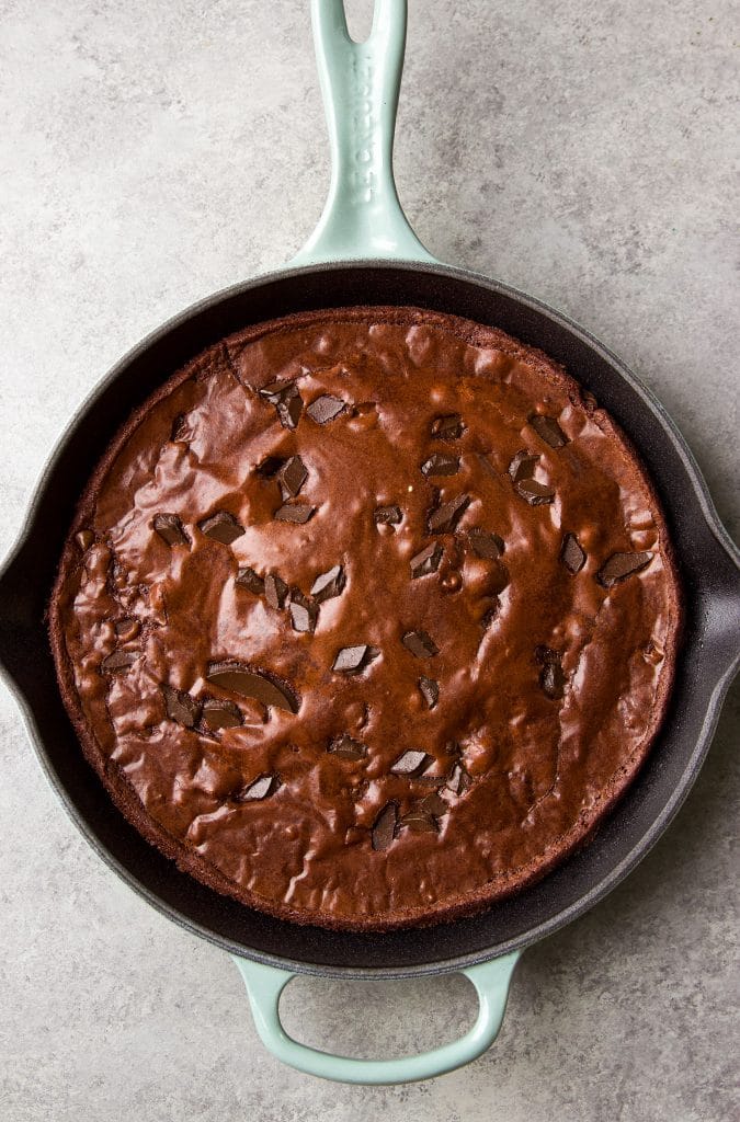 Brownies in a cast iron skillet with chocolate bits on top