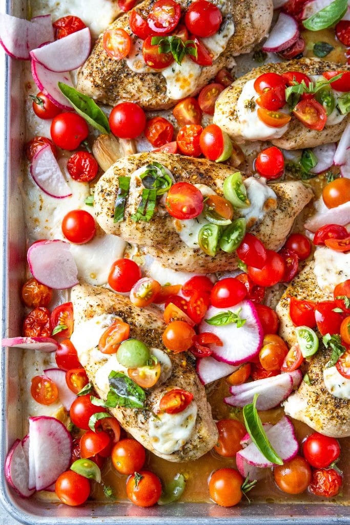 sheet pan bruschetta chicken topped with mozzarella cheese, tomatoes and basil
