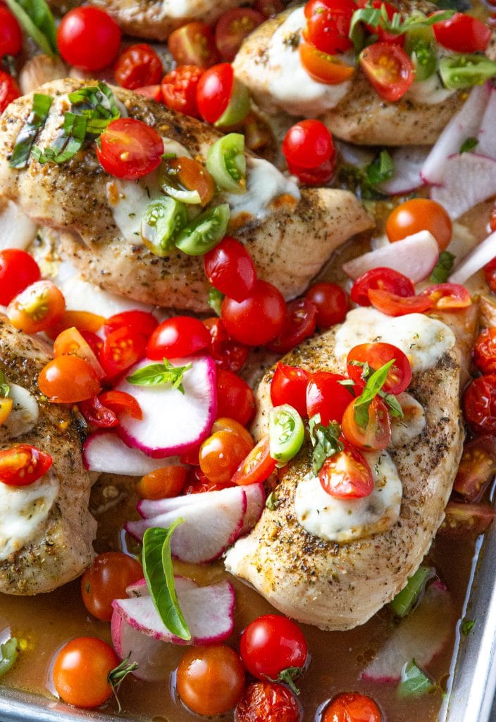 sheet pan bruschetta chicken topped with mozzarella cheese, tomatoes and basil
