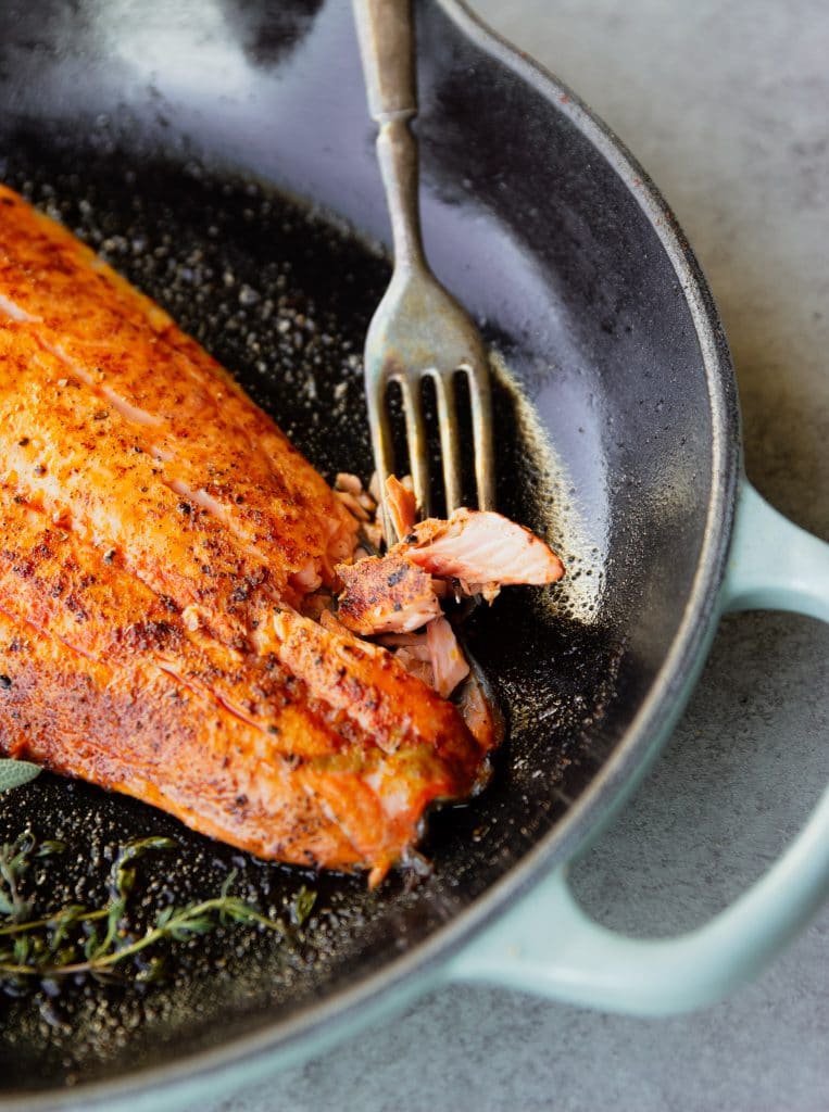 salmon filet in a cast iron skillet with herbs