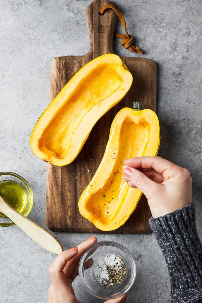 delicata squash being seasoned with salt and pepper.
