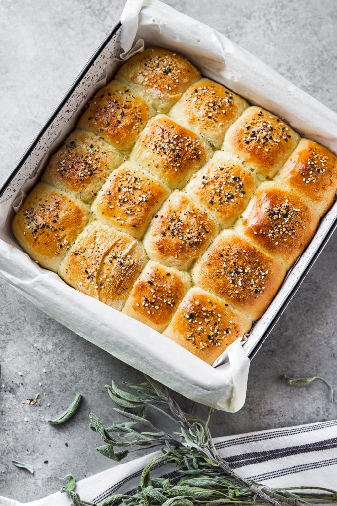 dinner rolls in baking dish. A dish towel and some dried herbs