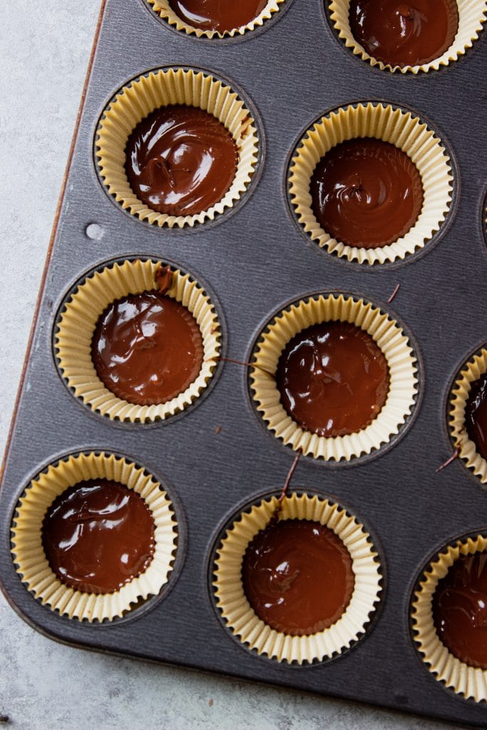 melted milk chocolate in silicone molds in a muffin tin.