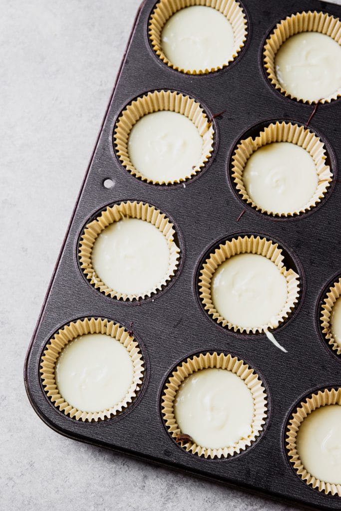melted white chocolate in silicone molds in a muffin tin.