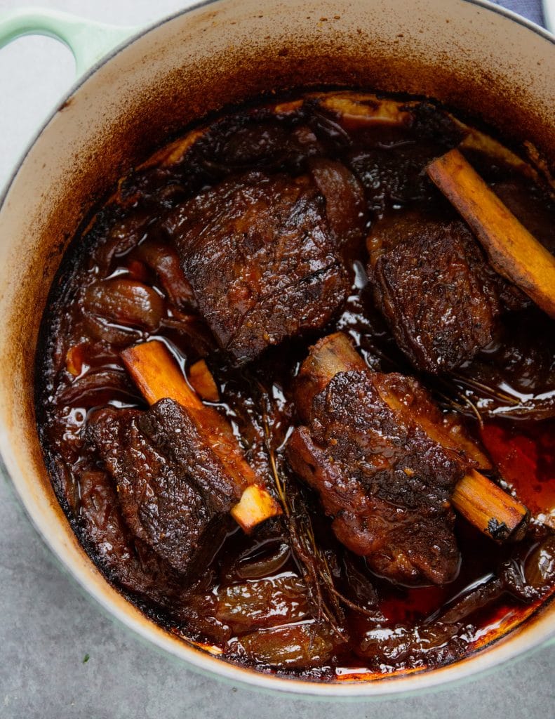 A dutch oven cast iron pot with oven braised short ribs.