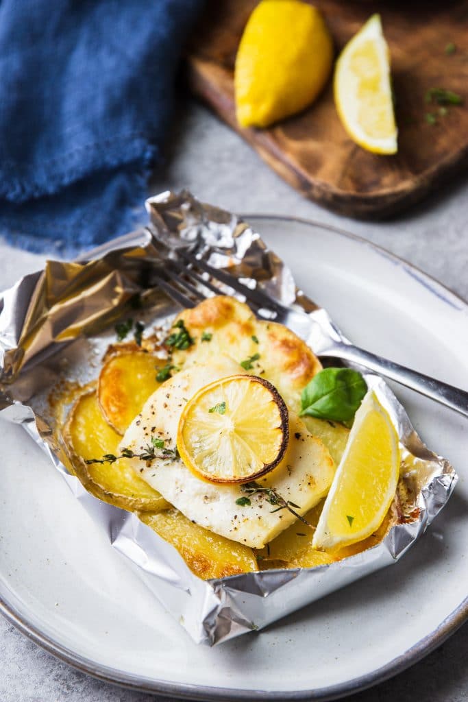 fish and potatoes baked in foil. A fish in foil packet on a plate with a fork