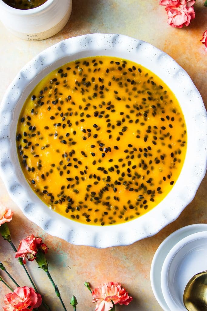 passion fruit mousse in white pie dish with pie flowers around