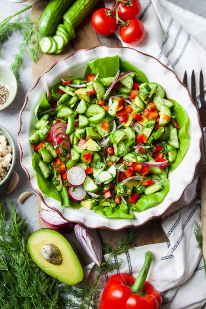 green salad with lettuce, tomatoes, avocado, onions and cucumbers