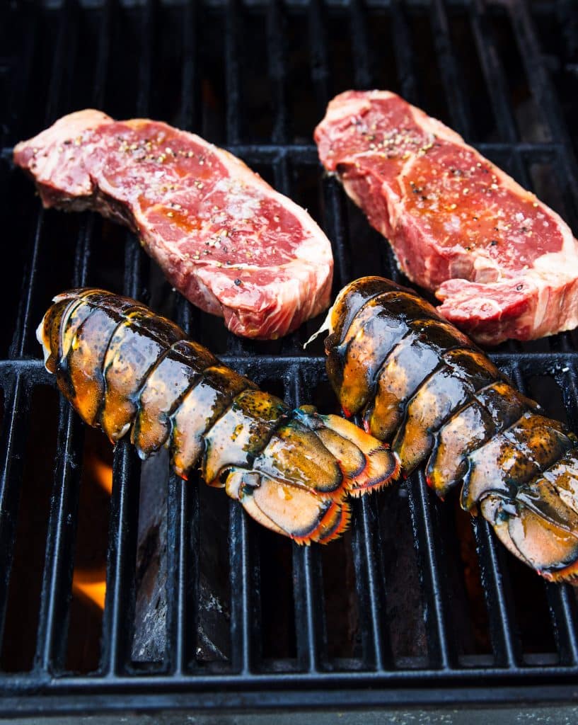 Two steaks and two lobster tails on the grill