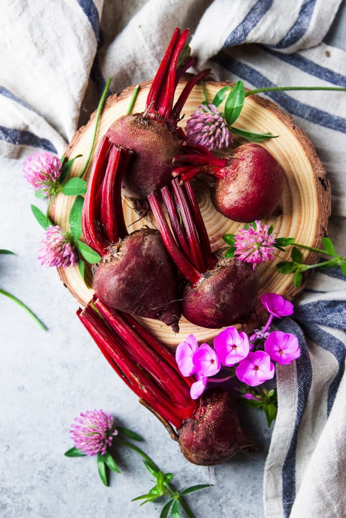 Fresh beets and fresh purple flowers. A rustic tablecloth. 