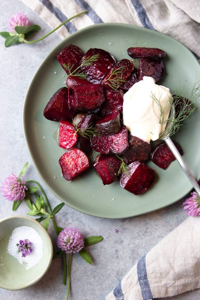 A plate with roasted beets topped with plant based yogurt and fresh dill