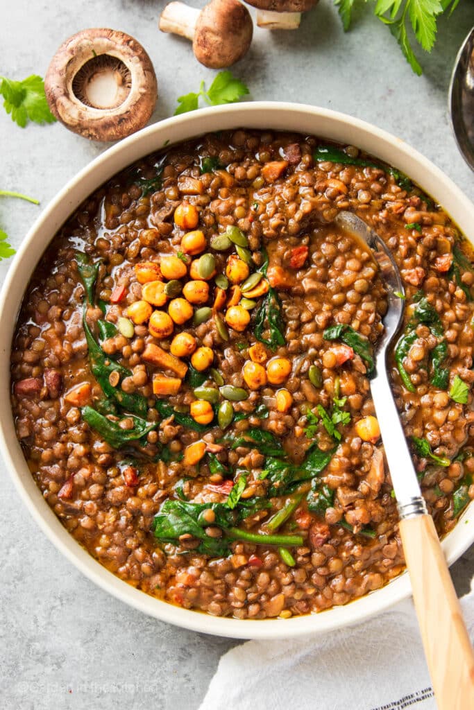A big bowl of instant pot French lentil soup topped with roasted chickpeas. 