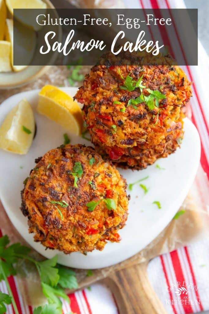 Two stacks of salmon cakes, fresh herbs and lemon on the table. 