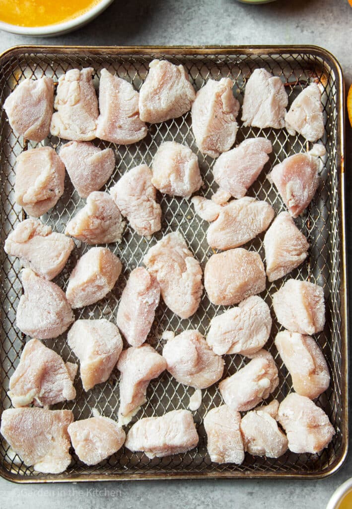 Cubed chicken in air fryer coved with cornstarch 