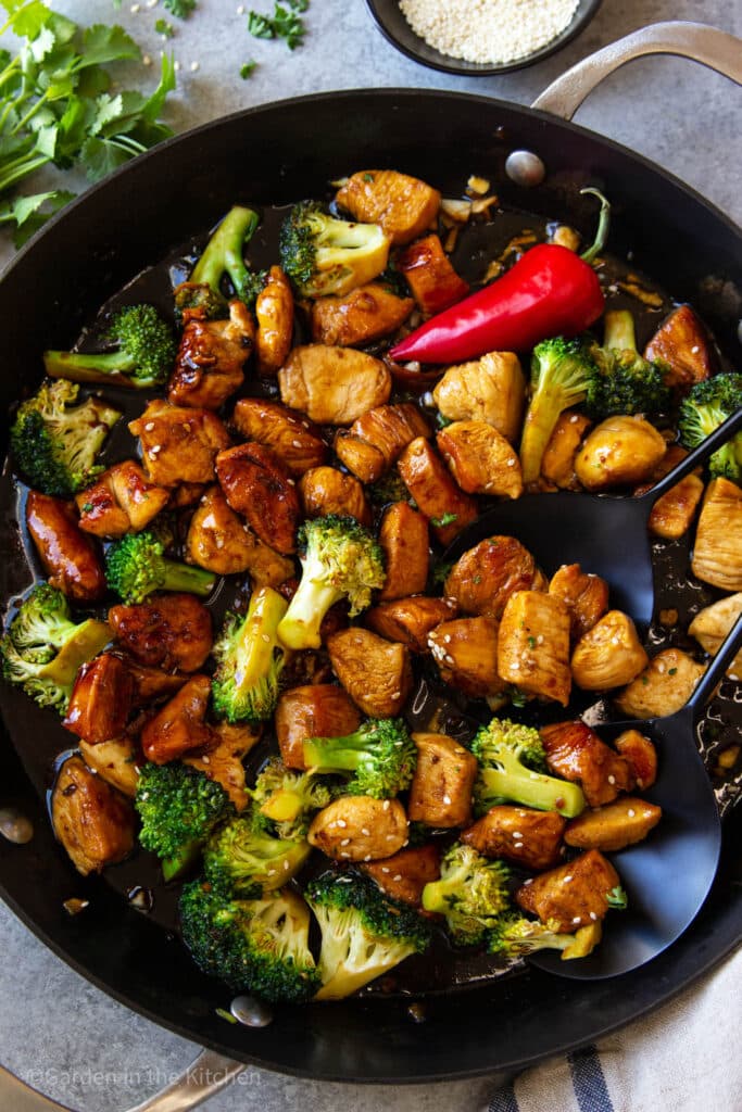 chicken and broccoli stir fry with asian flavors in a cast iron skillet with sesame seeds.