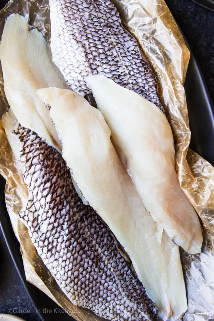 fresh sea bass filet on a plate with parchment paper