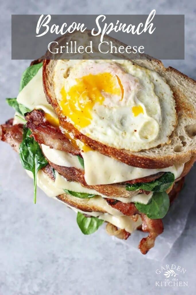 Grilled cheese with bacon and spinach stacked topped with a fried egg