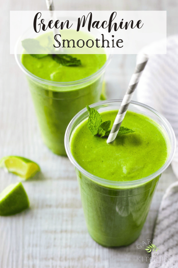 Two large glasses of green smoothie. A paper straw in each glass with mint garnishing. Lime slices on the table. 