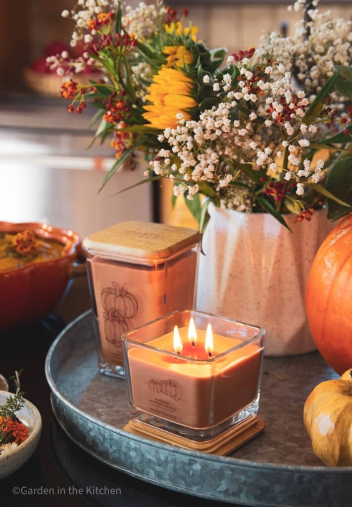 A fall arrangement with candles, flowers and pumpkins. 