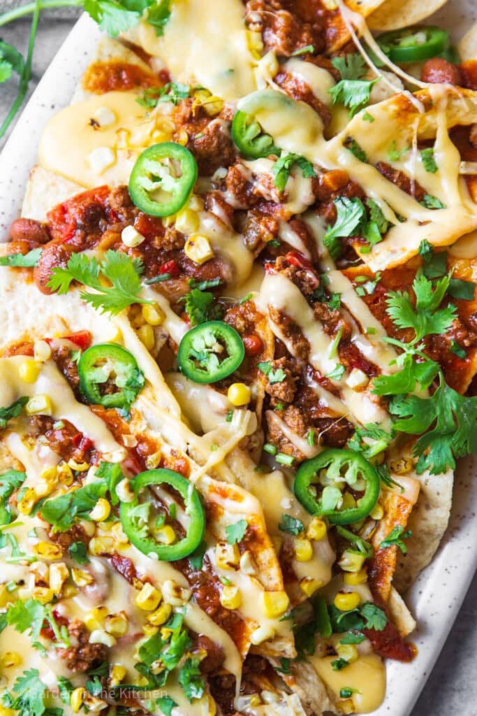 Nachos on a platter with chili, cheese, jalapeño, corn and cilantro. 