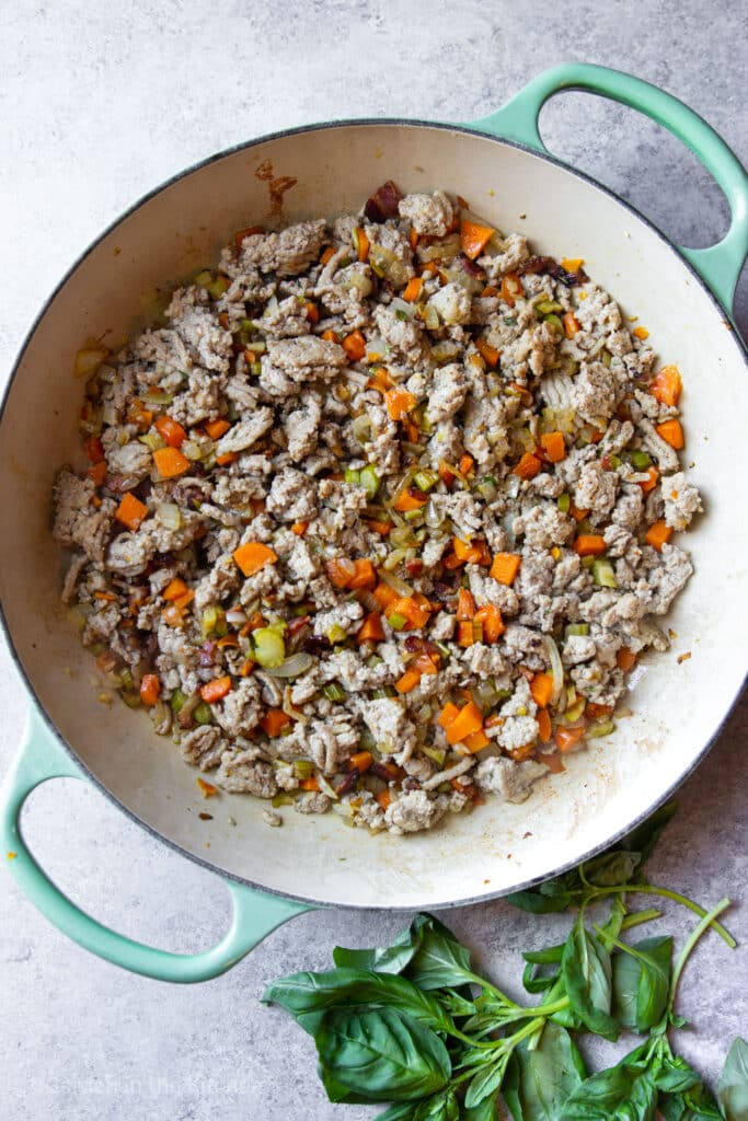A large skillet with chopped veggies and browned ground turkey meat. 