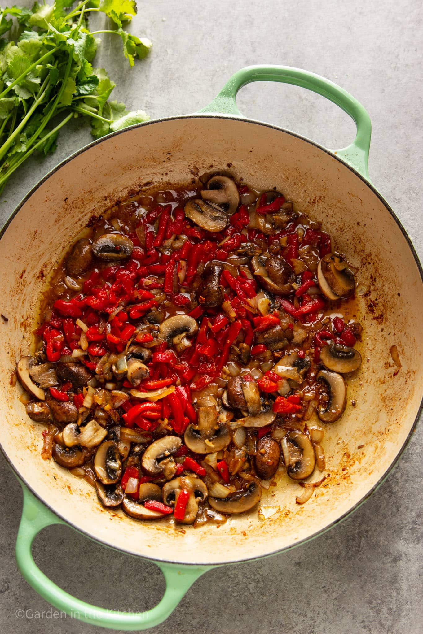 cooked onions, red peppers, and mushrooms in a pot.