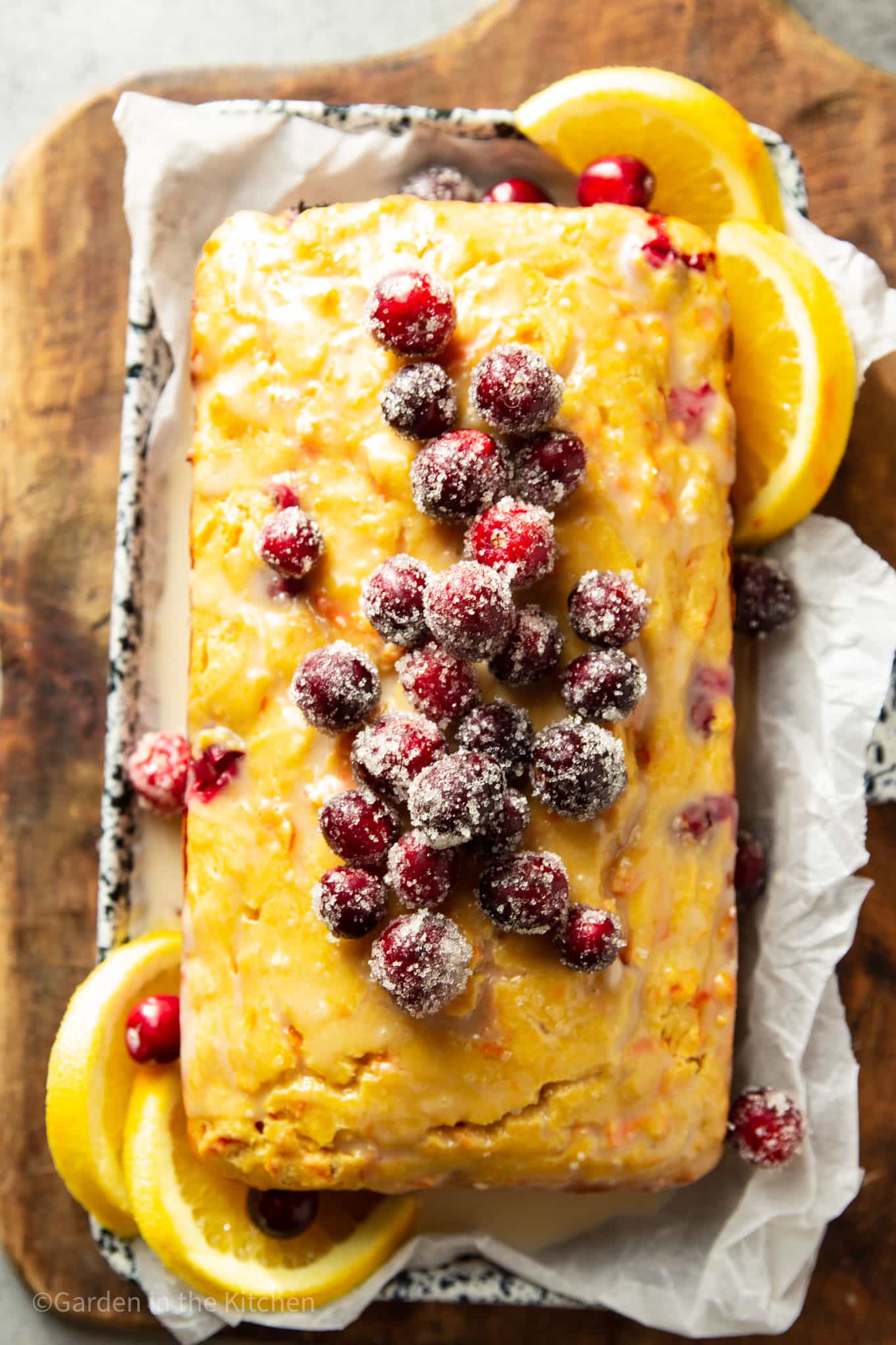 overhead view of a cranberry orange carrot cake topped with sugared cranberries.