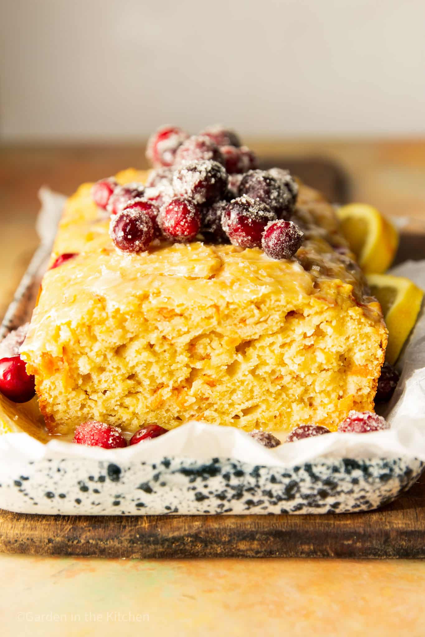 close up on a baked cranberry orange carrot cake topped with sugared cranberries.