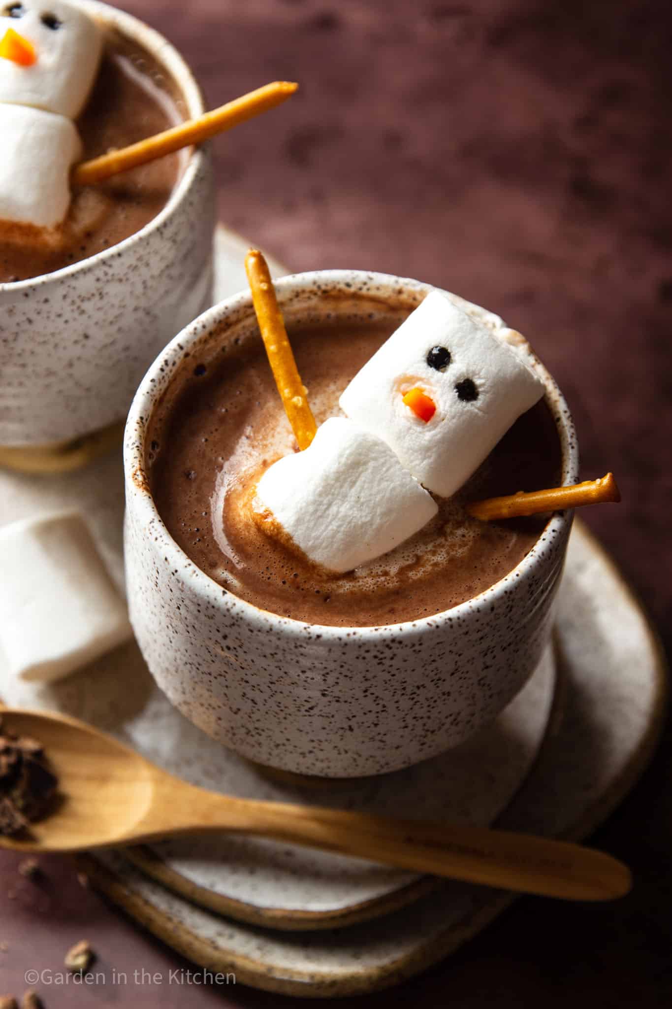 two mugs of Brazilian hot cocoa with marshmallow snowmen in each mug.