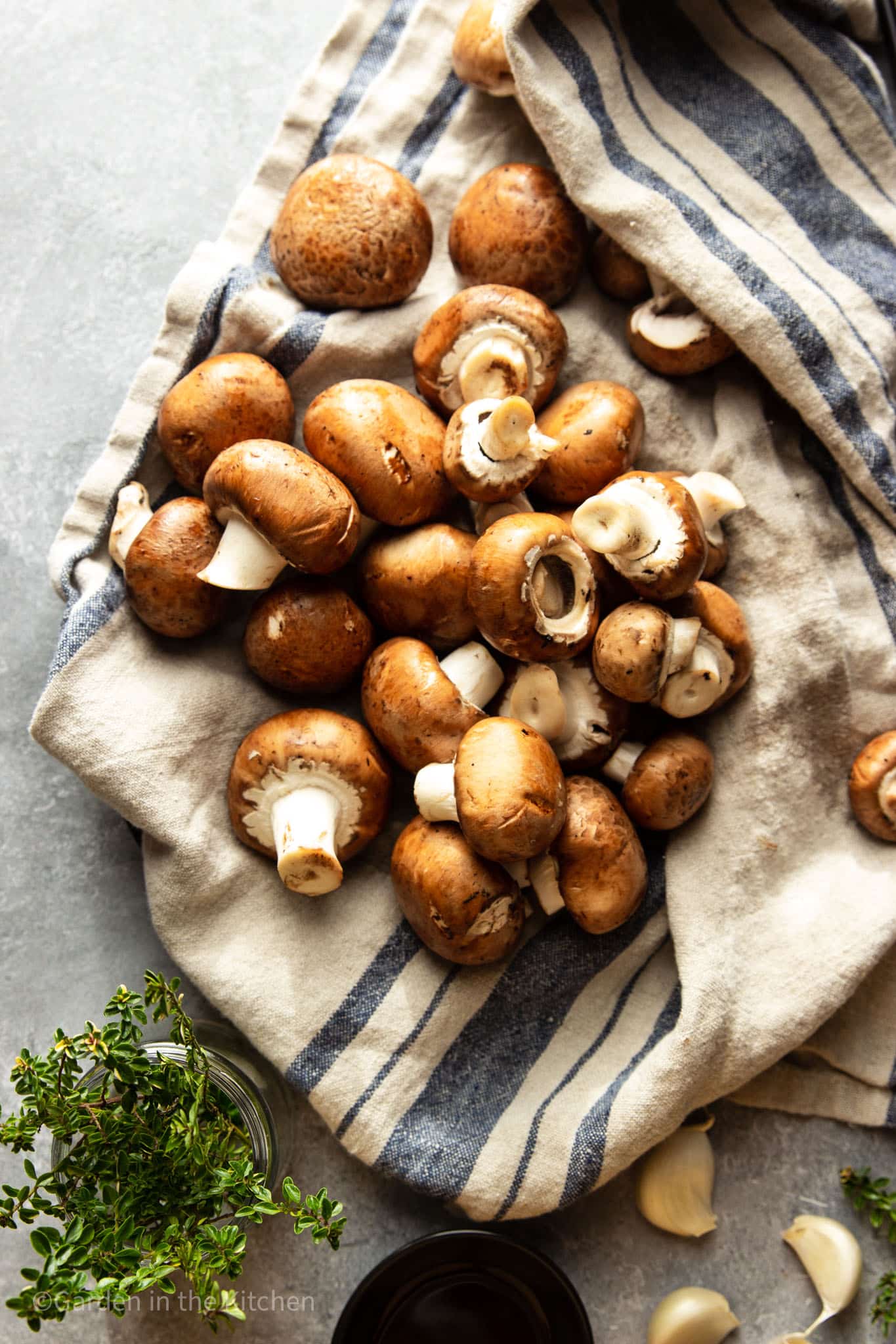 How to clean mushrooms using a dry towel. Fresh herbs and garlic on the table. 