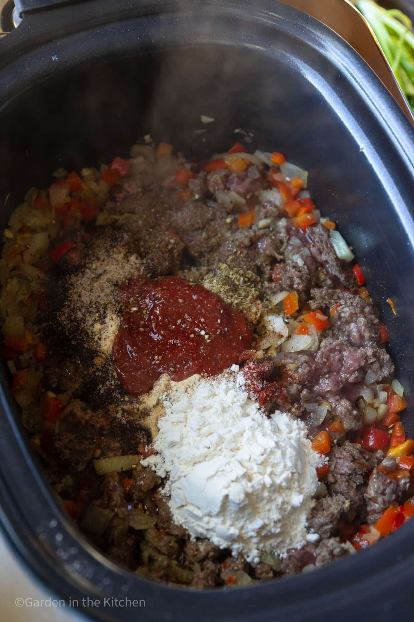 ingredients for venison chili cooking together in a large slow cooker.