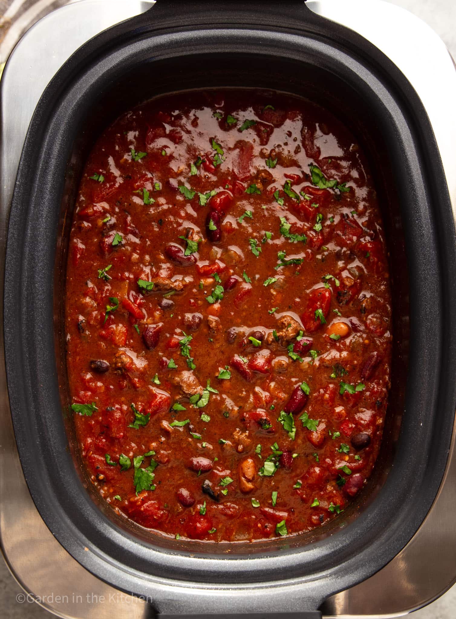 large black slow cooker filled with cooked venison chili.