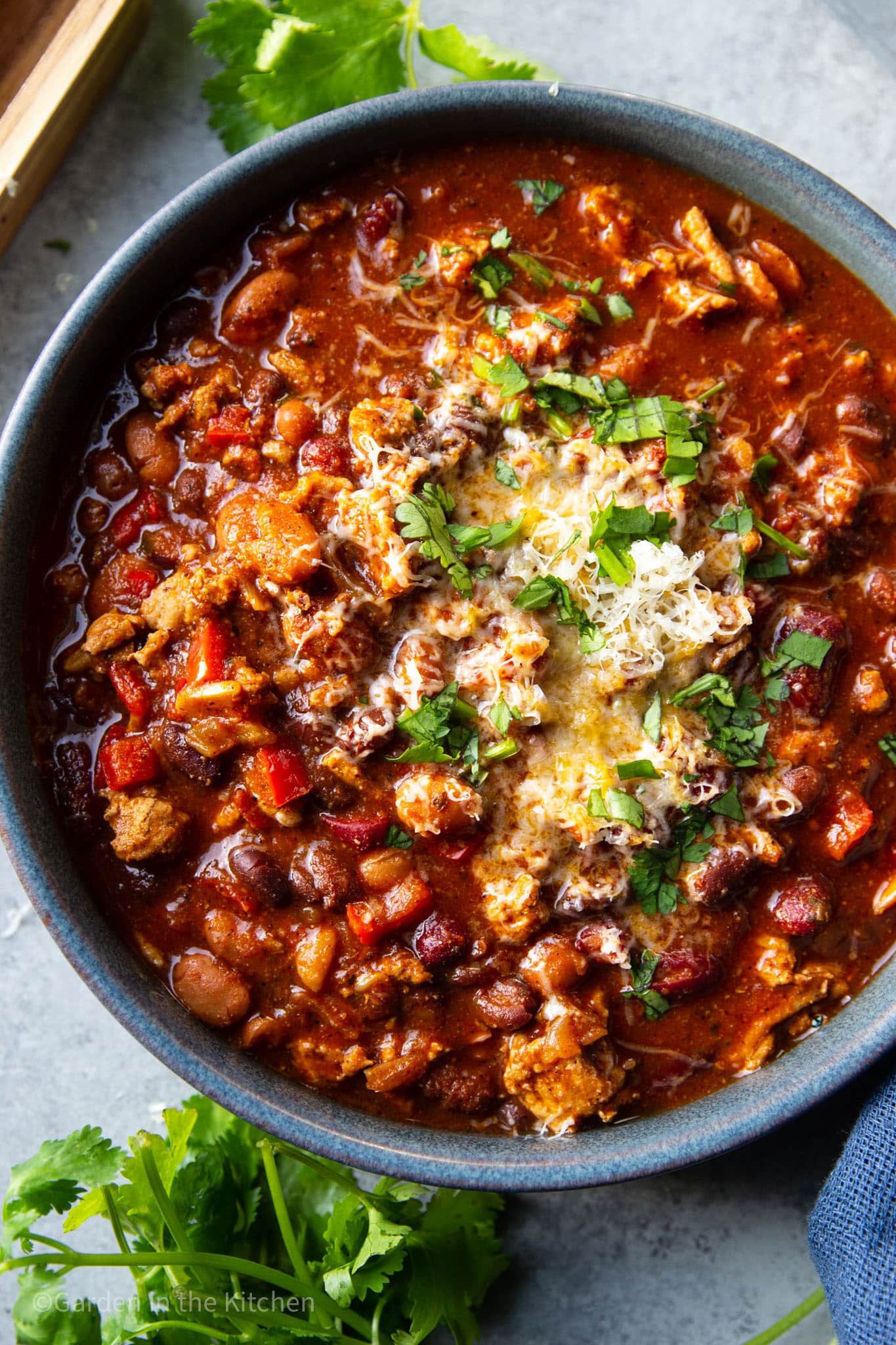 A big bowl of turkey chili with green herbs and cheese.